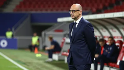 A photorealistic image of a 30-40-year-old, balding, bespectacled coach in a dark blue, polyester suit, with a white...