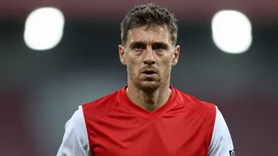 A photorealistic image of an anonymous 30-year-old FC Basel coach in a red jersey with white sleeves, looking focused and...