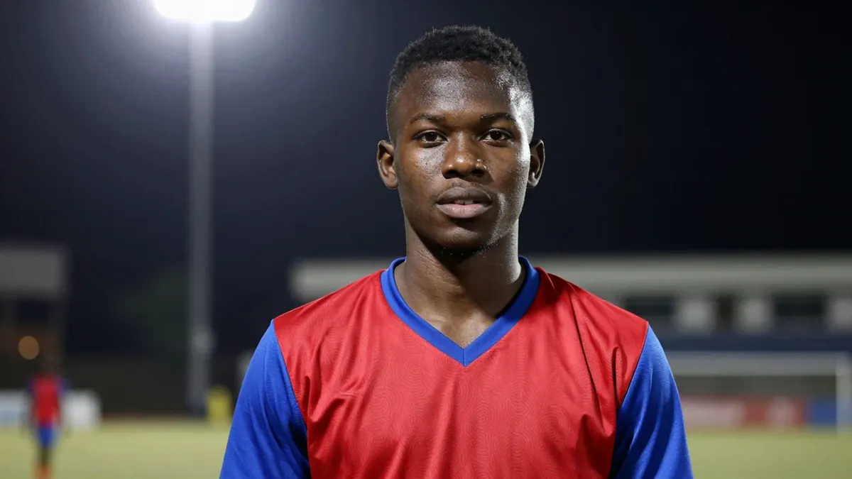 A young, dark-haired, 18-year-old Ghanaian midfielder with a muscular build, wearing a red and blue jersey, photographed...