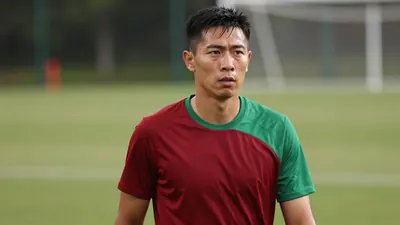 Mid-30s male coach, athletic build, waist-up, wearing a plain, unmarked training top split dark red and green, soft...