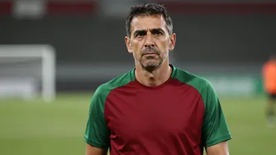 Middle-aged male coach, athletic build, mid-40s, intense expression, short dark hair, slight stubble, wearing a plain...
