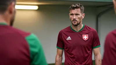 A 35-year-old Swiss defensive midfielder, wearing a plain unmarked dark red and green polyester home kit, his face set in...