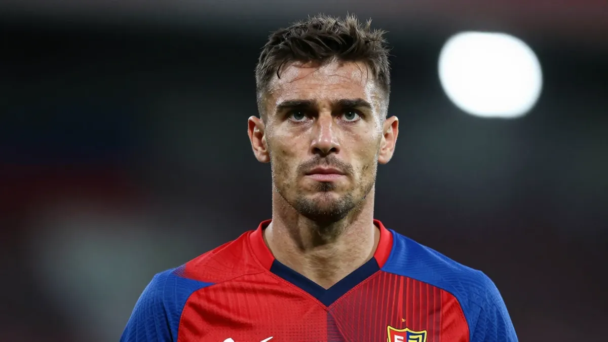 A 30-year-old FC Basel coach with a strong build, wearing a red and blue kit