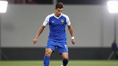 A photorealistic image of a 26-year-old French football player wearing a blue kit with a white shirt and blue shorts...