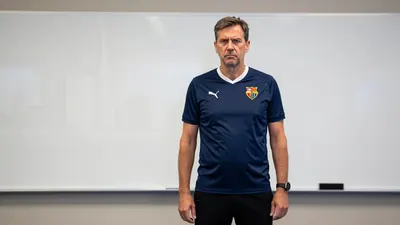 A photorealistic image of an anonymous FC Basel coach in his mid-40s, with a stern expression, standing in front of a...